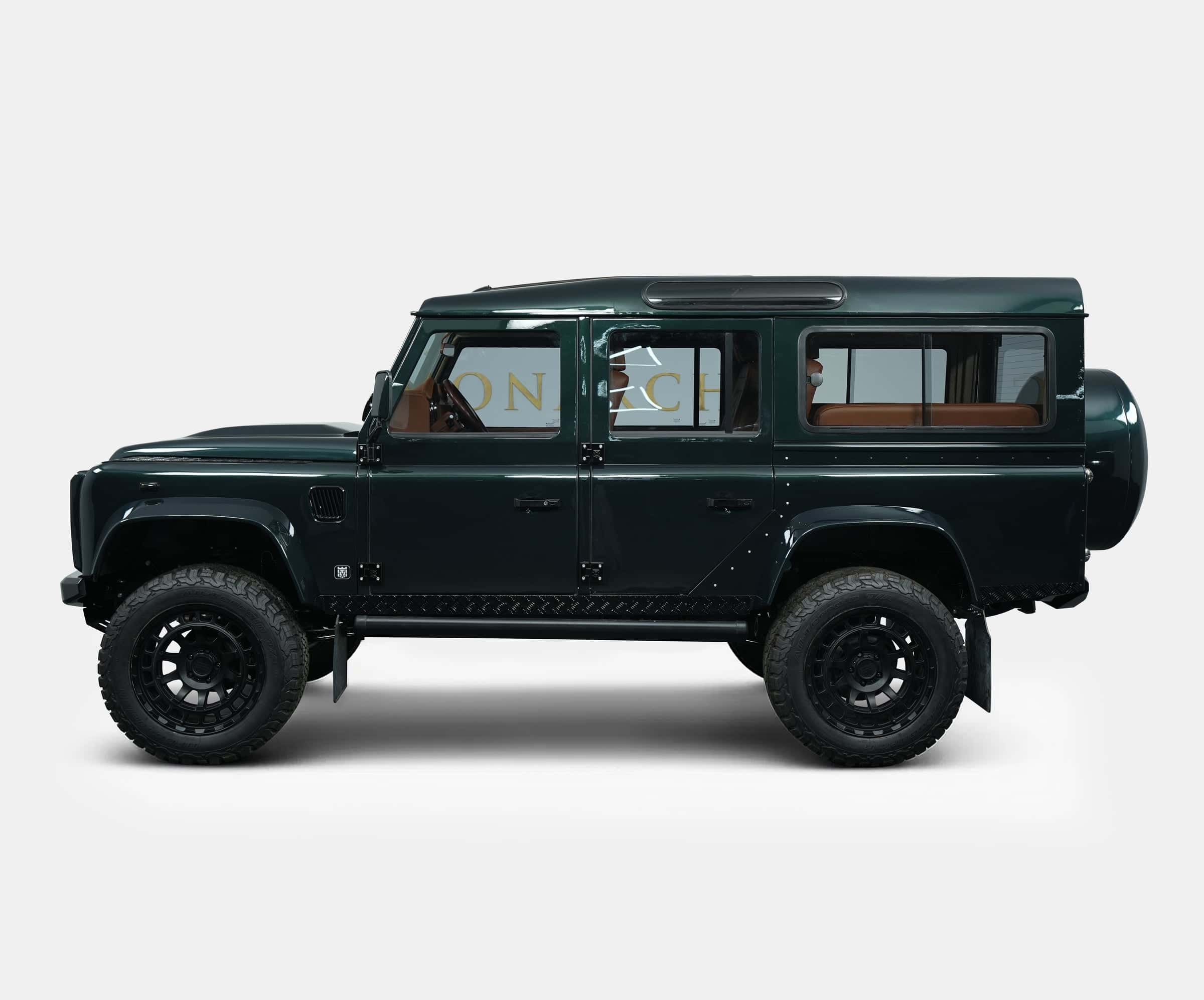 Side view of a bespoke Land Rover Defender in dark green with luxury tan interior