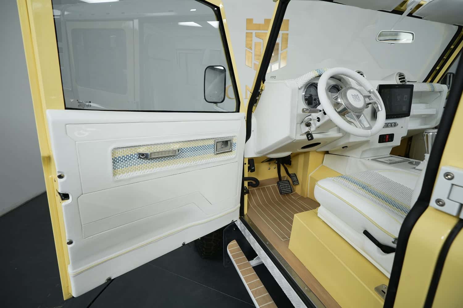 Interior view of a luxury custom Land Rover Defender featuring white leather upholstery and yellow accents