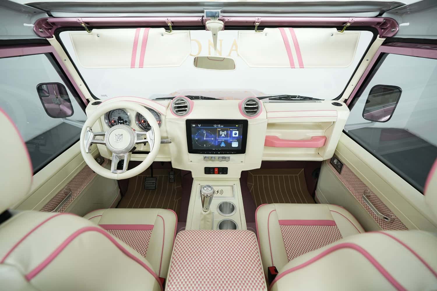 Bespoke Land Rover Defender interior featuring cream and pink leather, modern dashboard, and touchscreen display