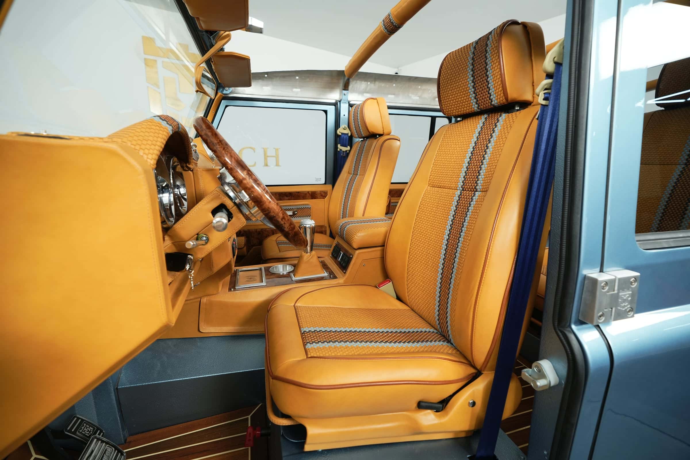 Interior of a bespoke Land Rover Defender featuring tan leather seats with blue accents