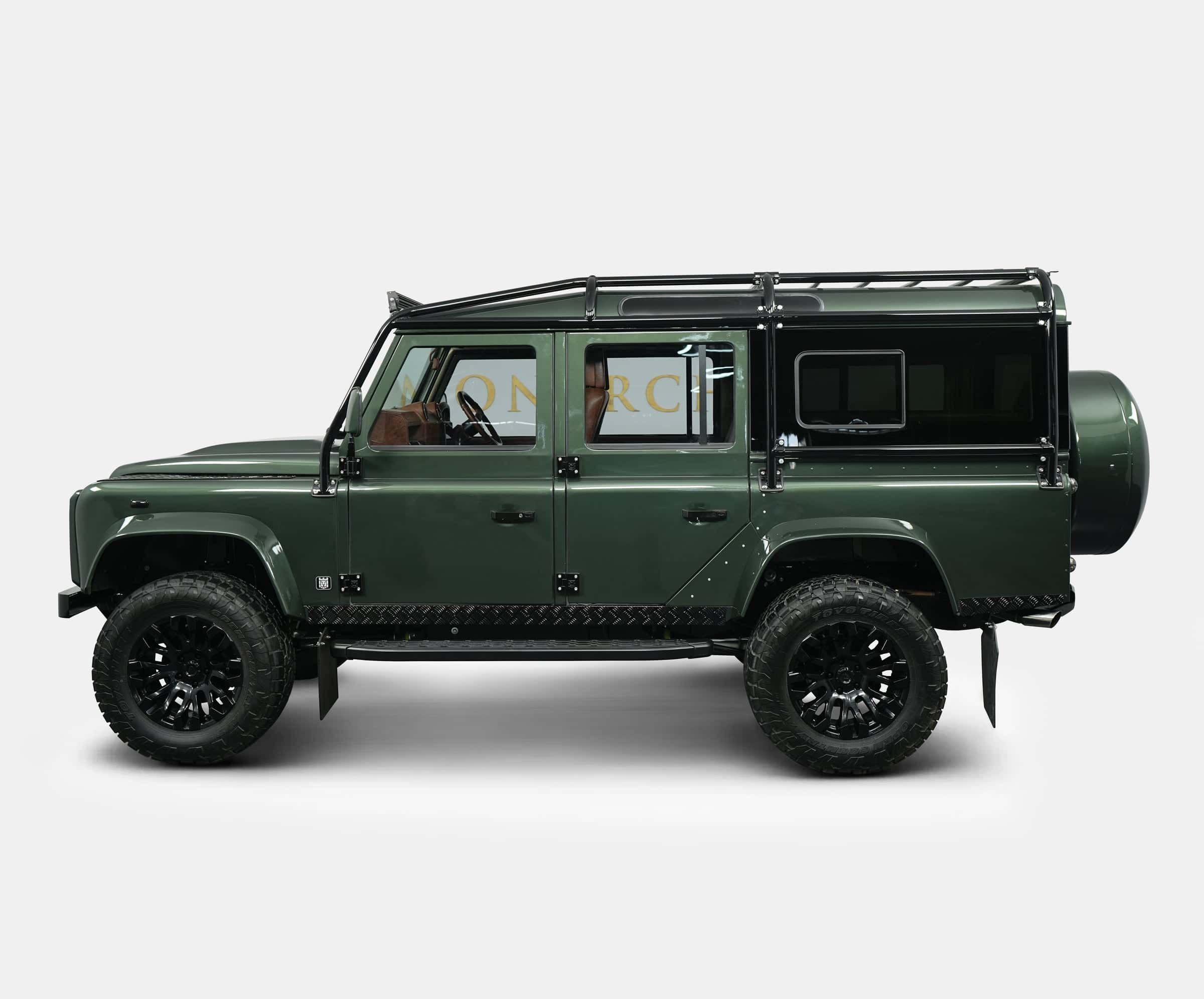 Side view of a bespoke green Land Rover Defender with off-road tires and luxury details