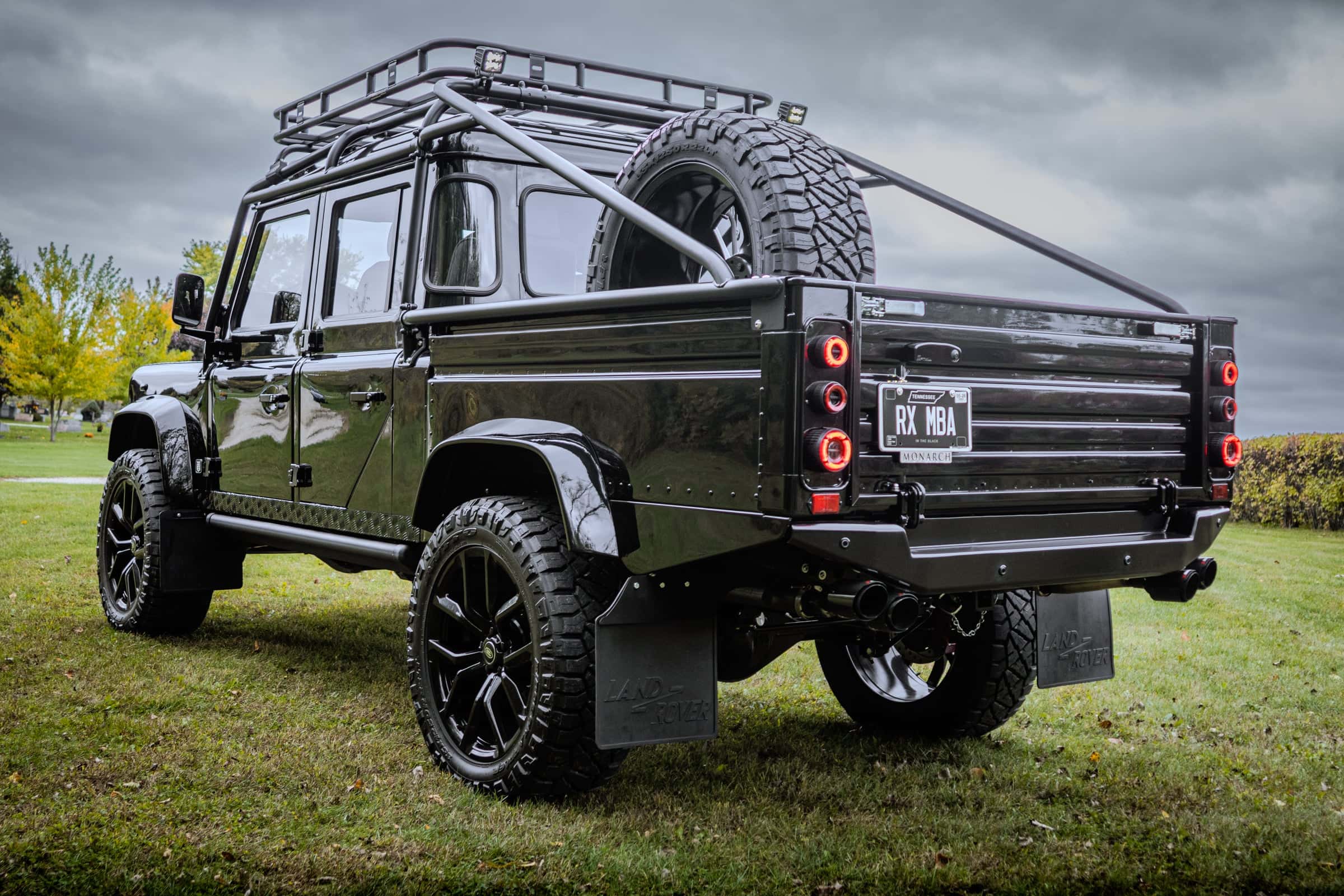 Custom black Land Rover Defender with a rugged exterior and spare tire mounted on the back