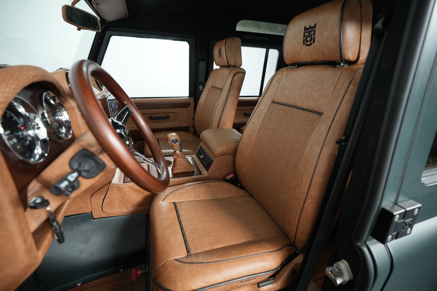 Interior view of a luxury Land Rover Defender with tan leather seats and wooden steering wheel