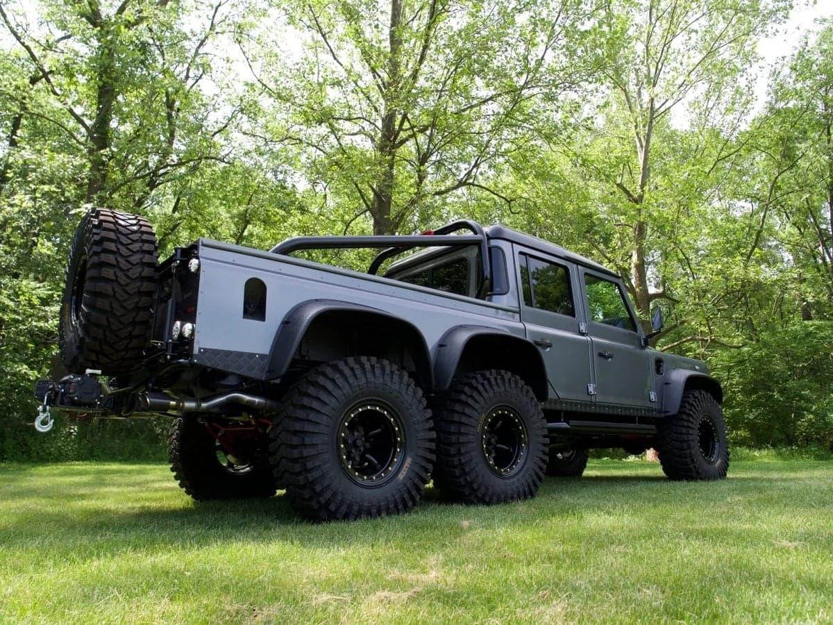 Custom Land Rover Defender in grey with large off-road tires parked in a grassy area