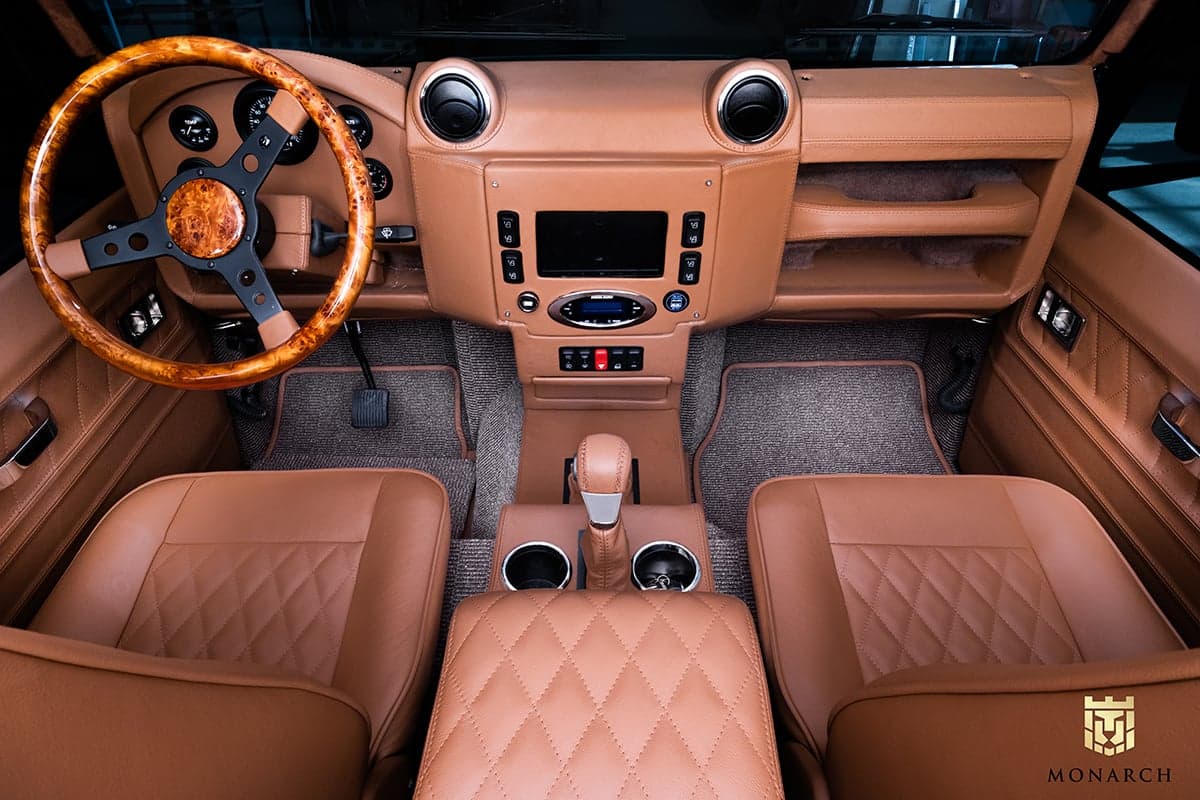 Luxurious interior of a custom Land Rover Defender with premium tan leather seats and wooden steering wheel