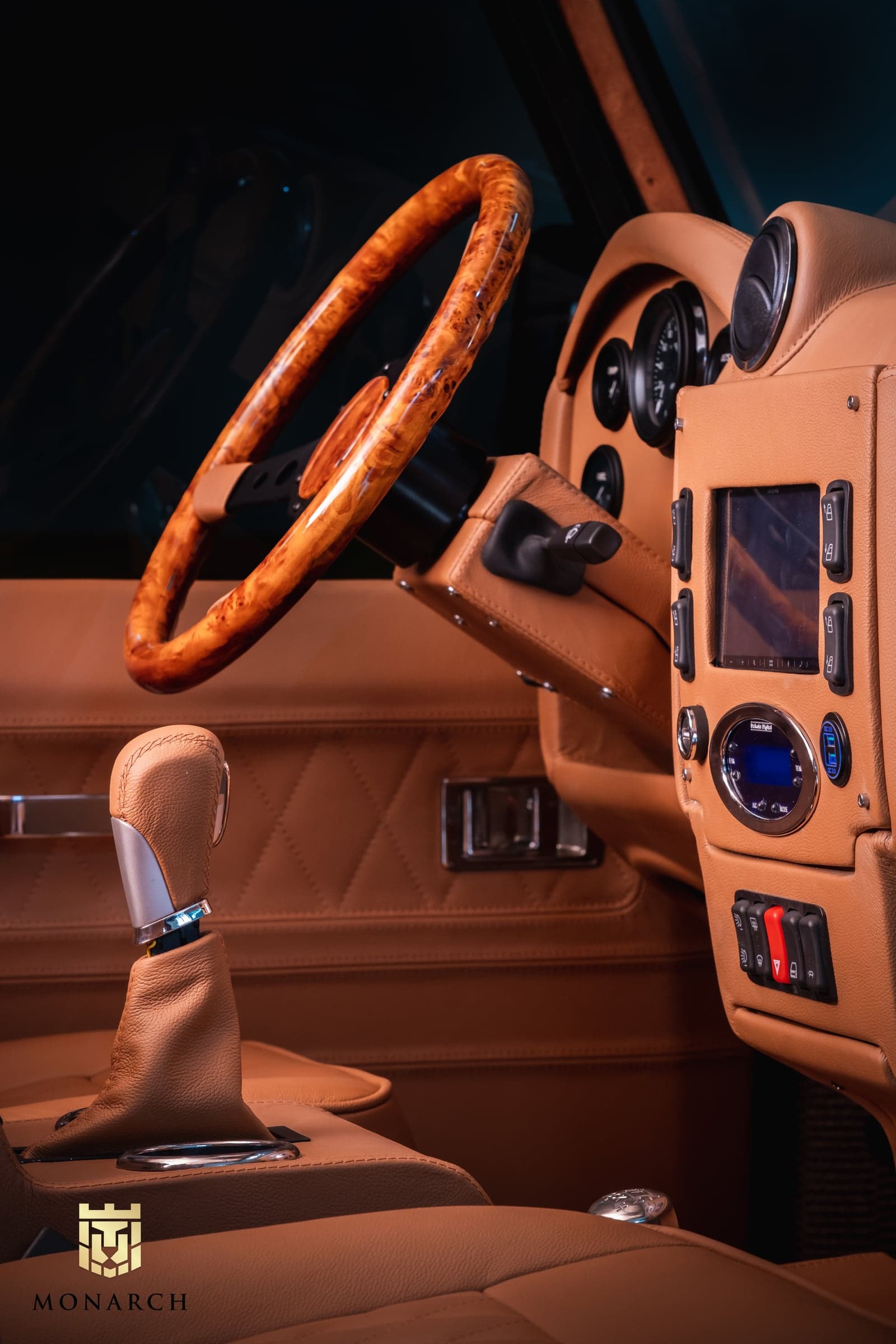 Close-up of a luxury Land Rover Defender interior featuring a wooden steering wheel, leather seats, and modern controls
