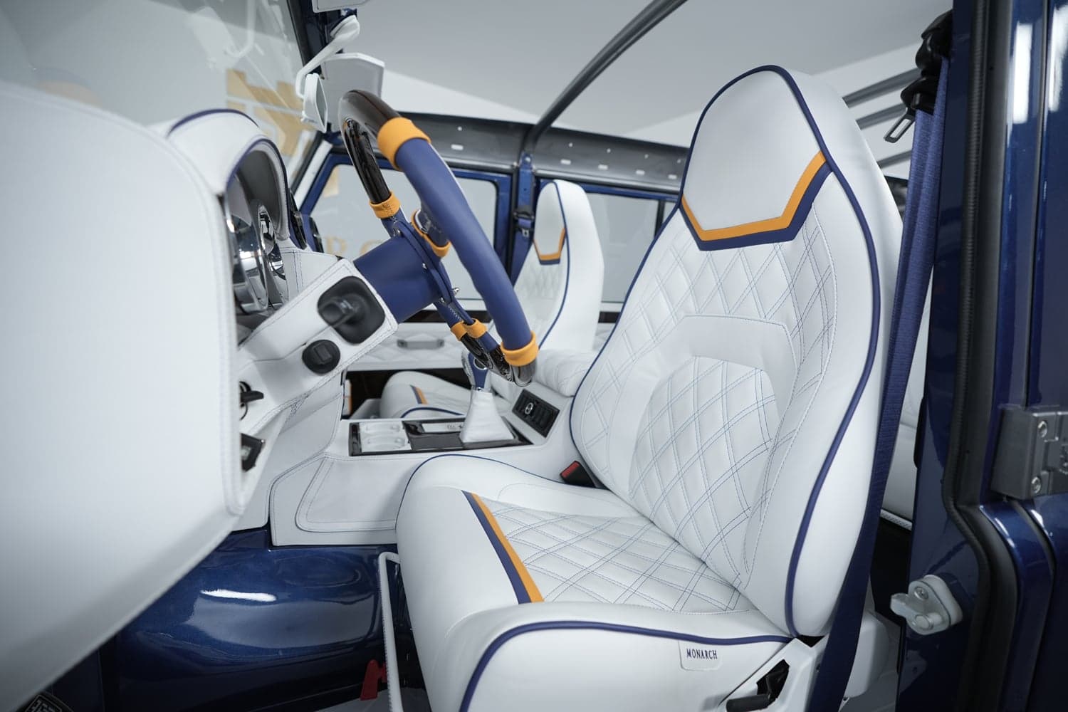 Custom Land Rover Defender interior featuring white leather seats with orange and blue accents