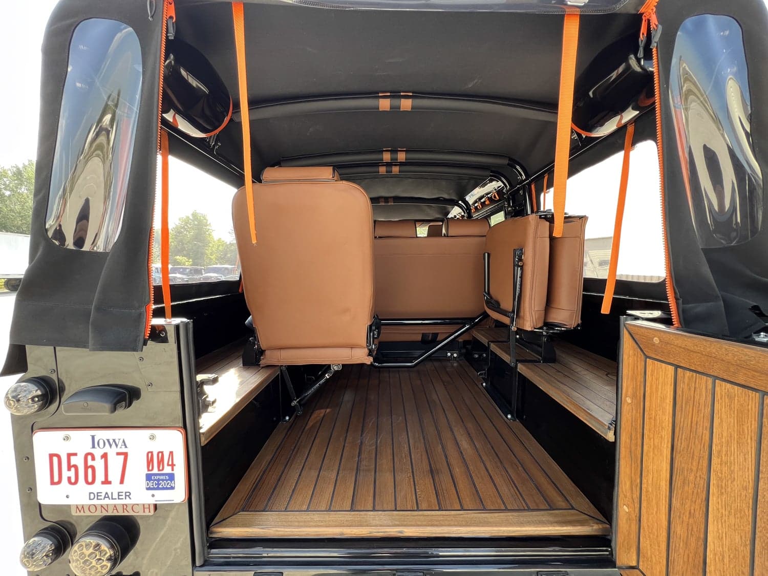 Interior view of a bespoke Land Rover Defender showing custom brown leather seating and wooden flooring