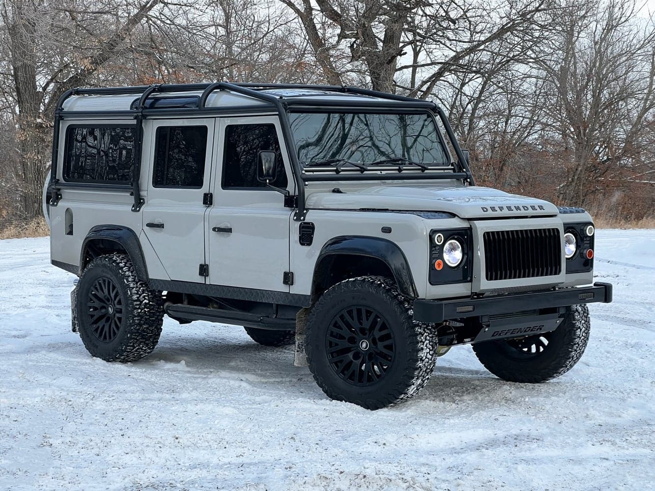 Custom Land Rover Defender in a snowy landscape with premium black rims and rugged exterior