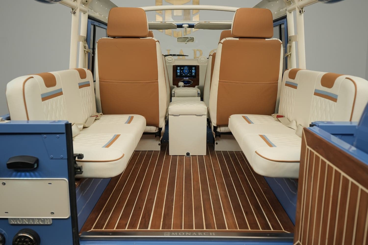 Interior view of a luxury custom Land Rover Defender with tan and cream seating and wooden flooring