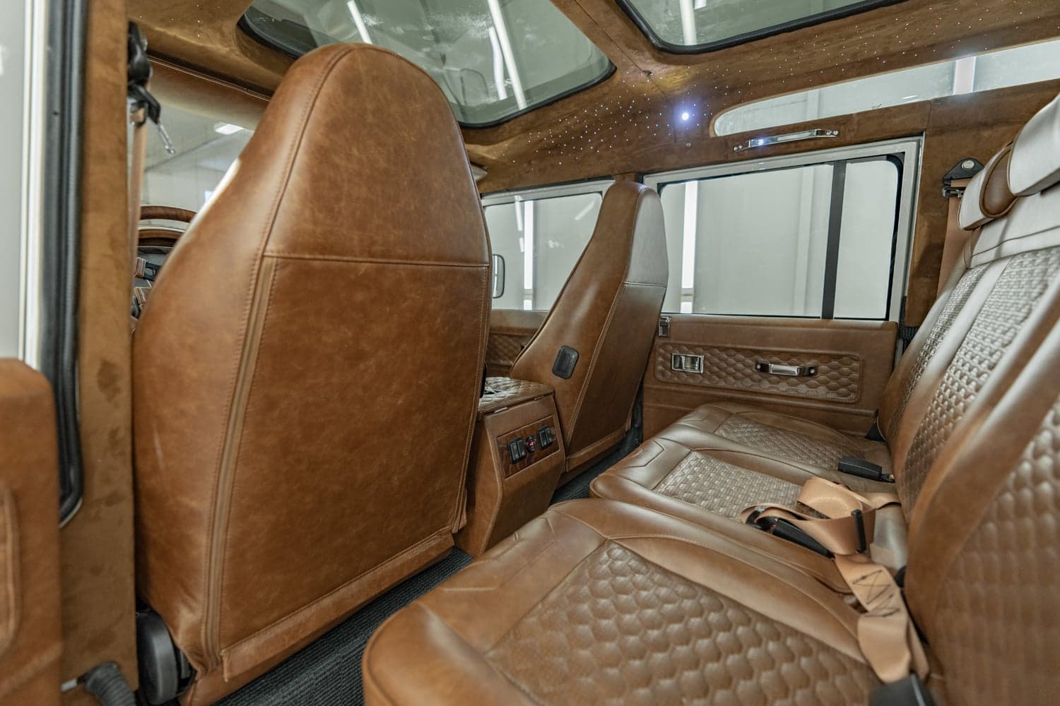 Interior view of a luxury Land Rover Defender featuring tan leather seats and detailed upholstery