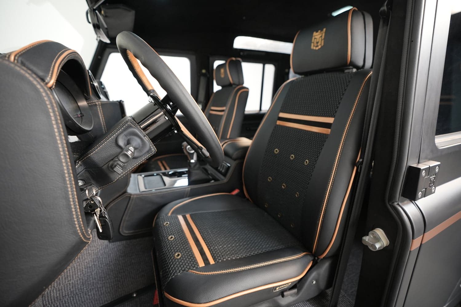Custom Land Rover Defender interior with premium black leather seats and orange stitching