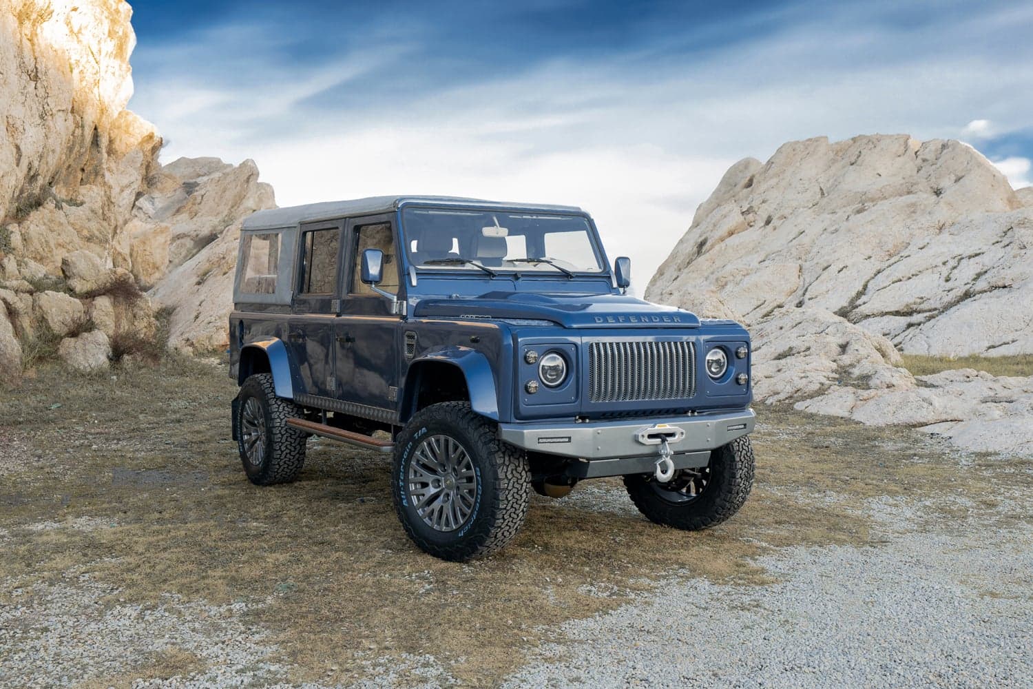 Custom blue Land Rover Defender parked on rocky terrain
