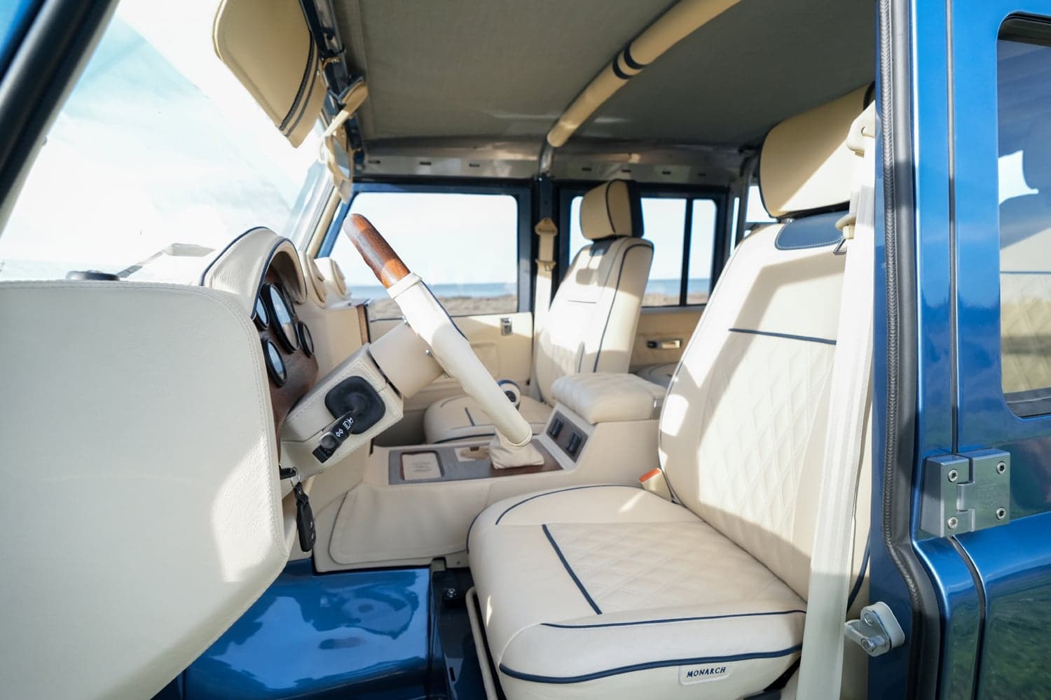 Interior view of a bespoke Land Rover Defender with cream leather seats and wooden accents