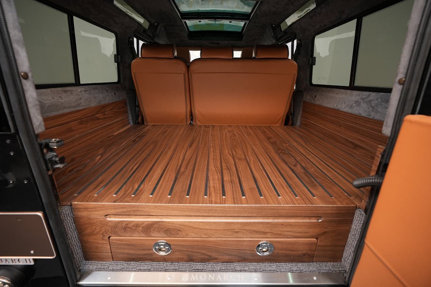 Interior view of a luxury Land Rover Defender with custom wood flooring and leather seats