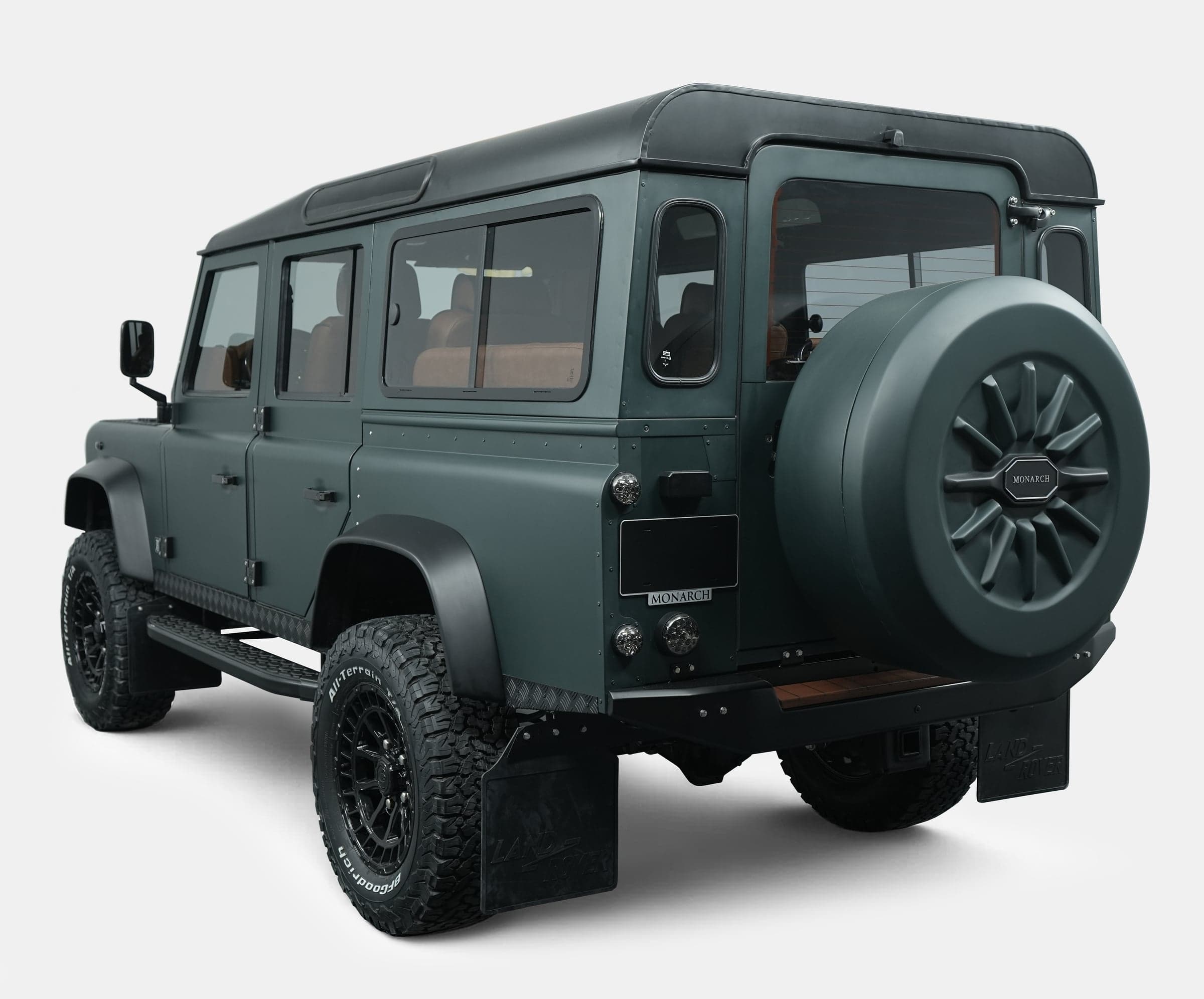 Rear view of a bespoke Land Rover Defender in matte green finish with custom wheels and spare tire