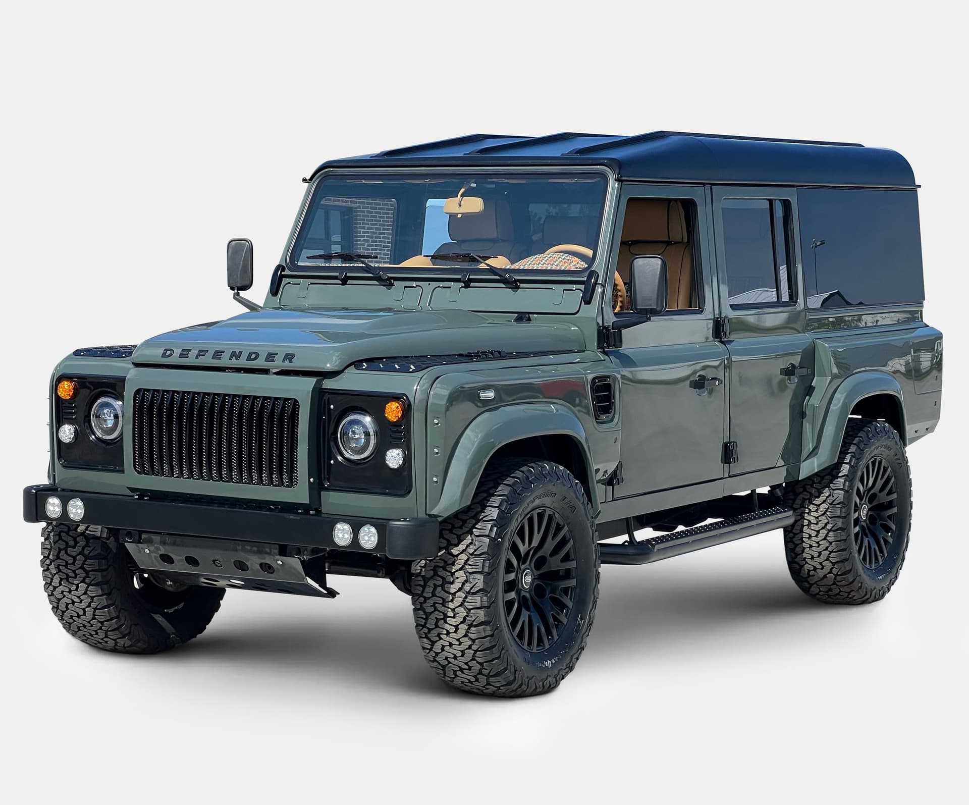 Front view of a bespoke Land Rover Defender in green with black accents and luxury wheels