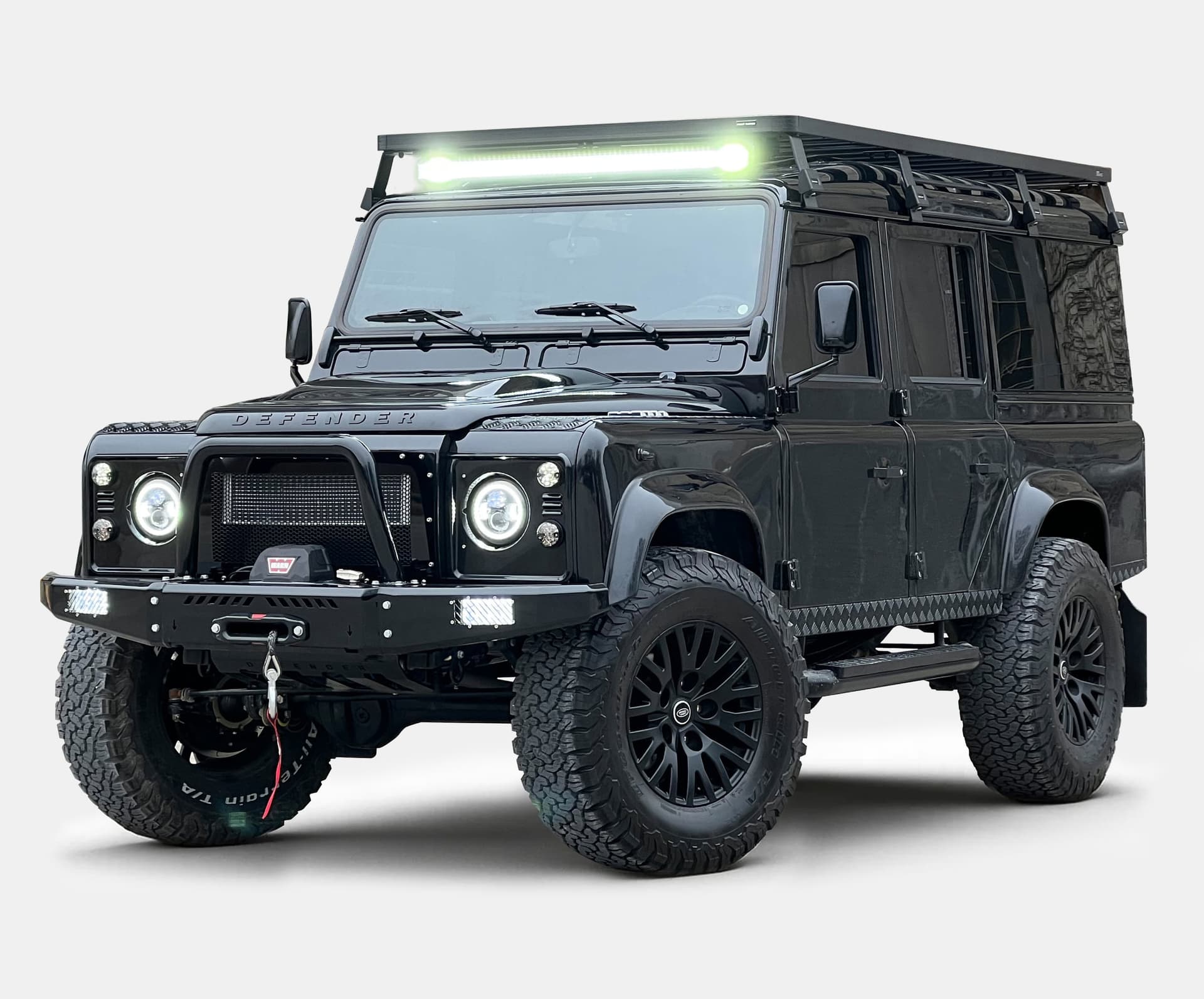 Custom black Land Rover Defender with off-road features and LED light bar