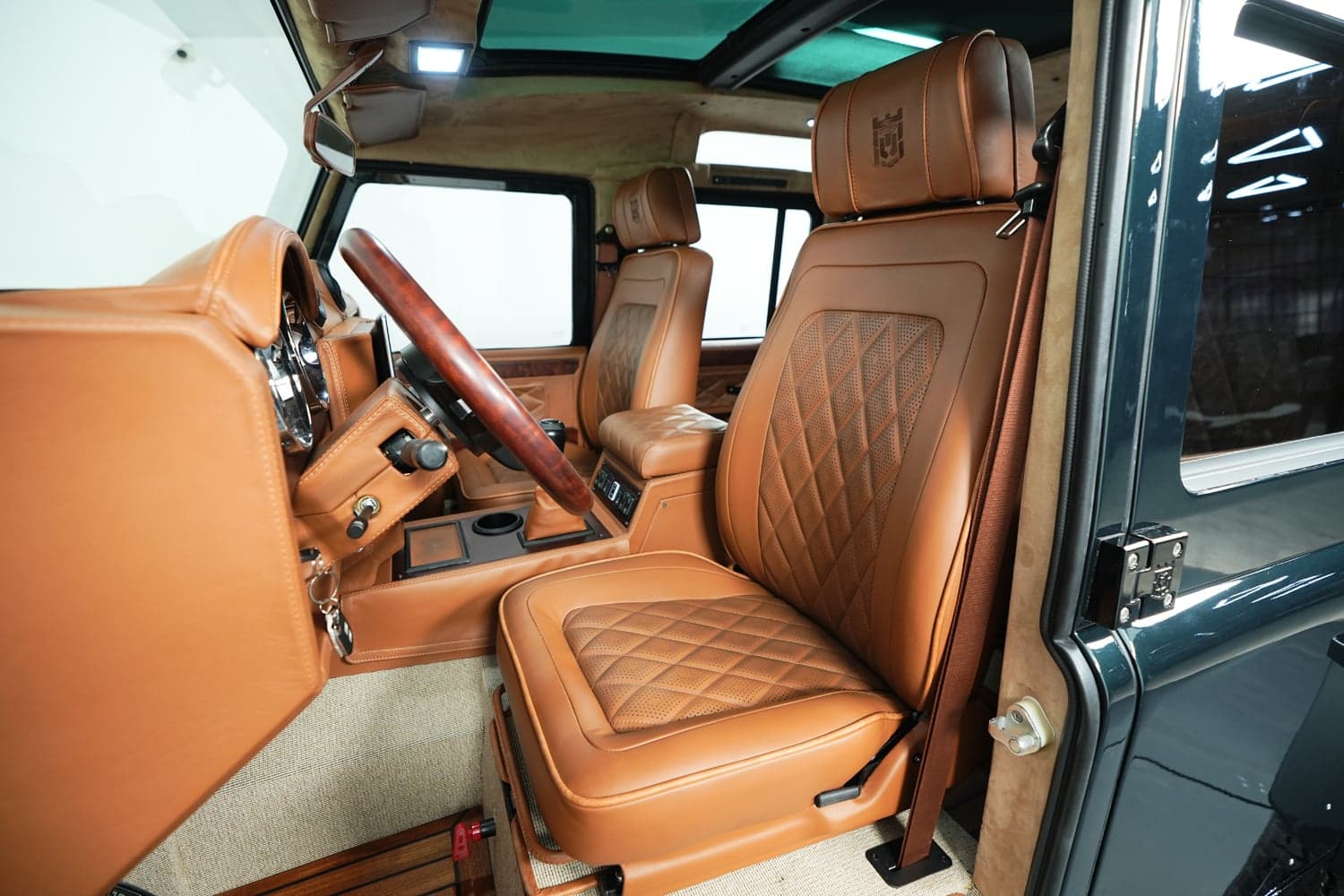 Interior view of a luxury Land Rover Defender featuring tan leather seats and wood accents