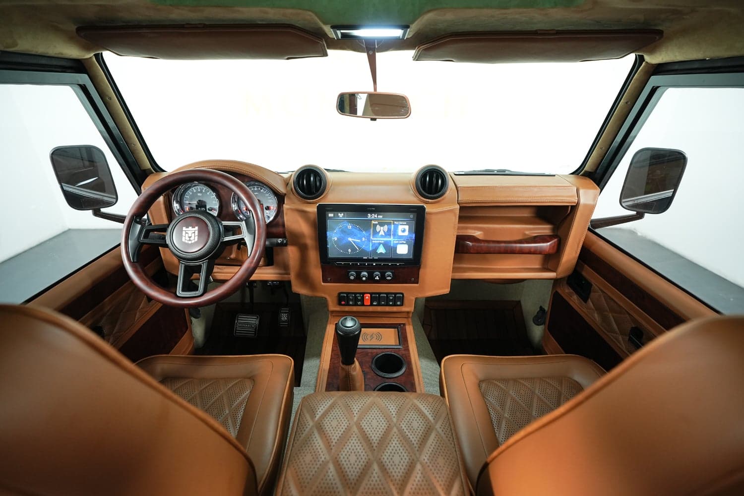 Interior view of a custom Land Rover Defender featuring premium tan leather seats and modern technology