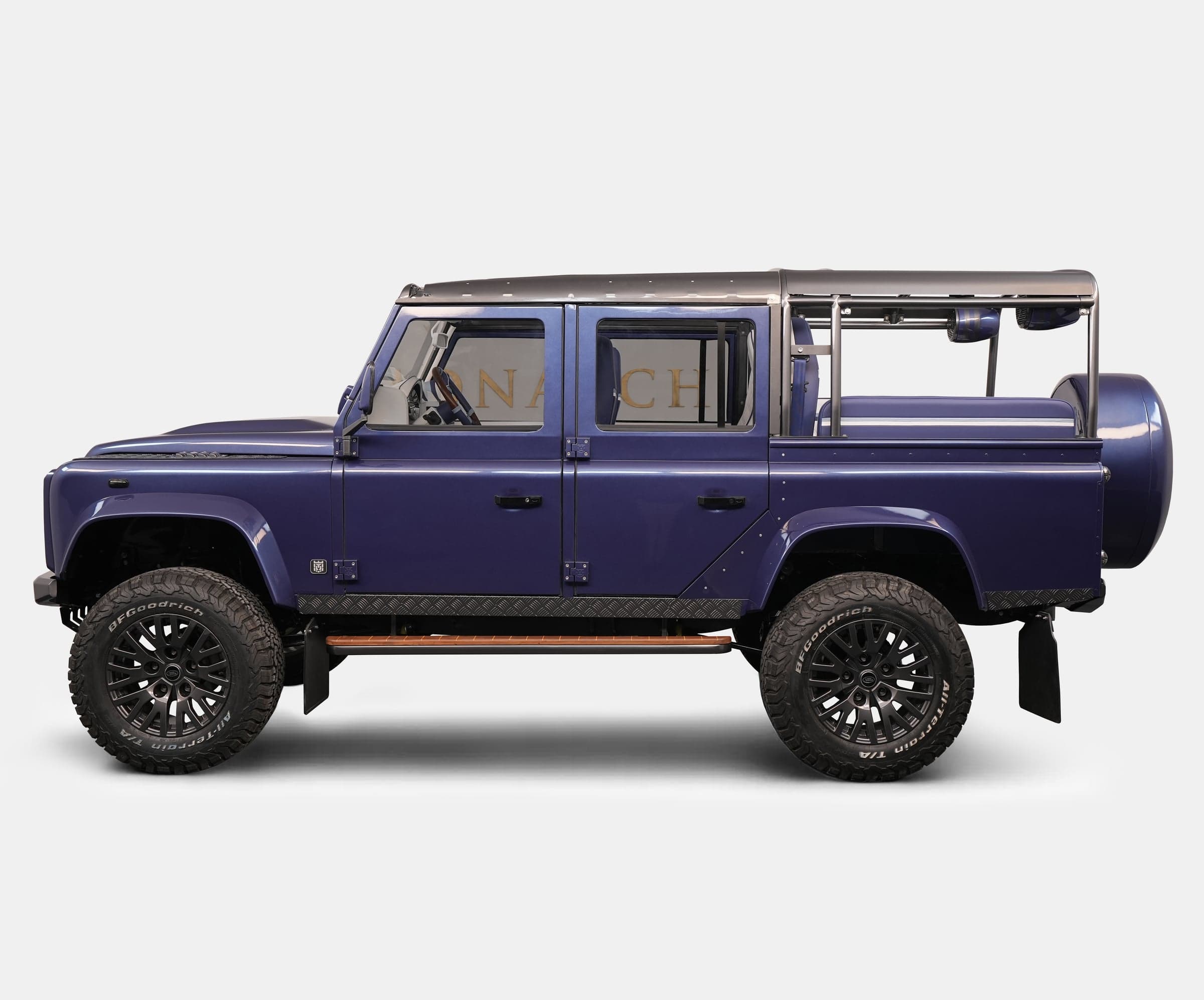 Side view of a bespoke Land Rover Defender in deep purple with off-road tires and custom features