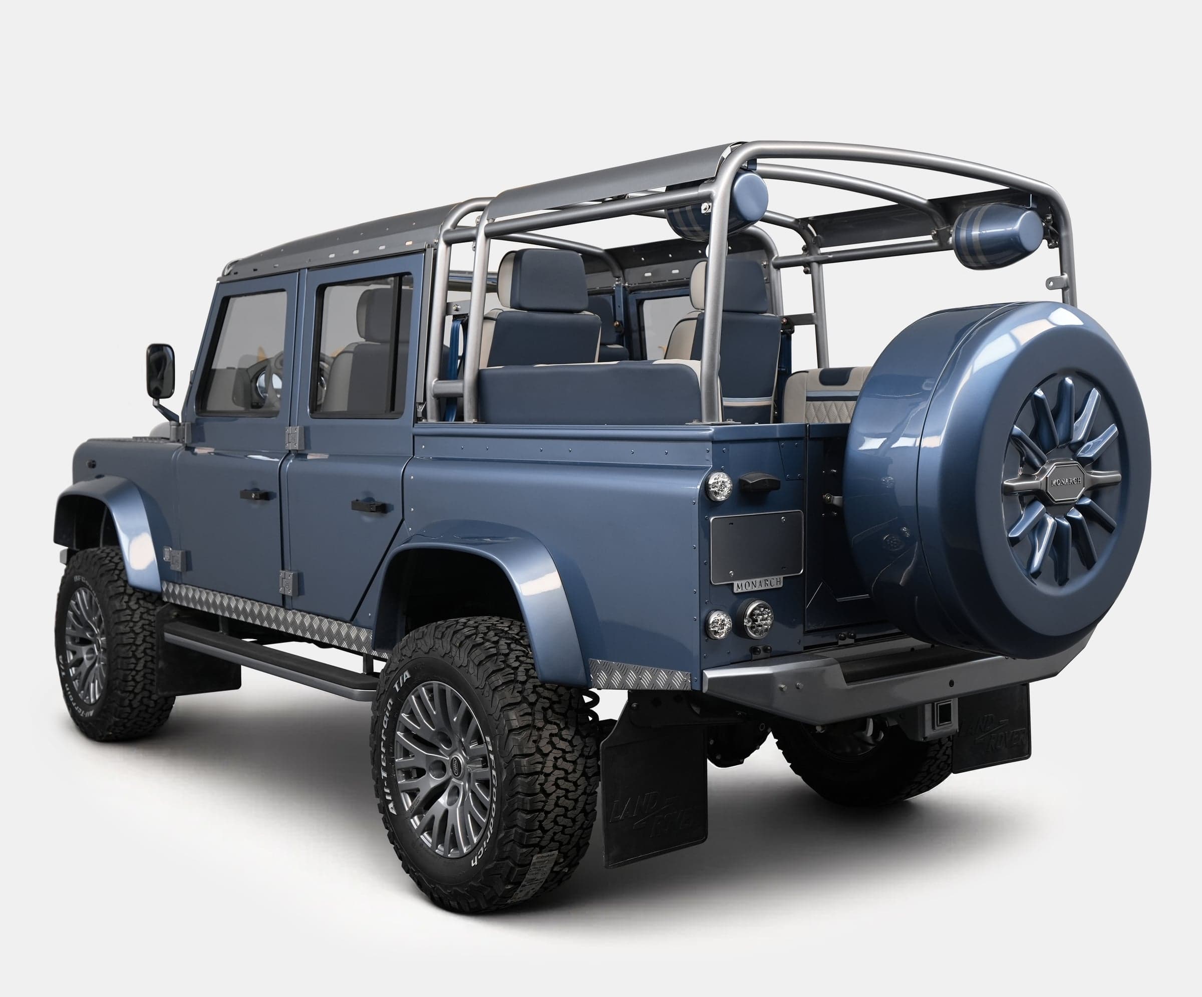 Rear view of a custom blue Land Rover Defender with a stylish spare tire and luxurious seating
