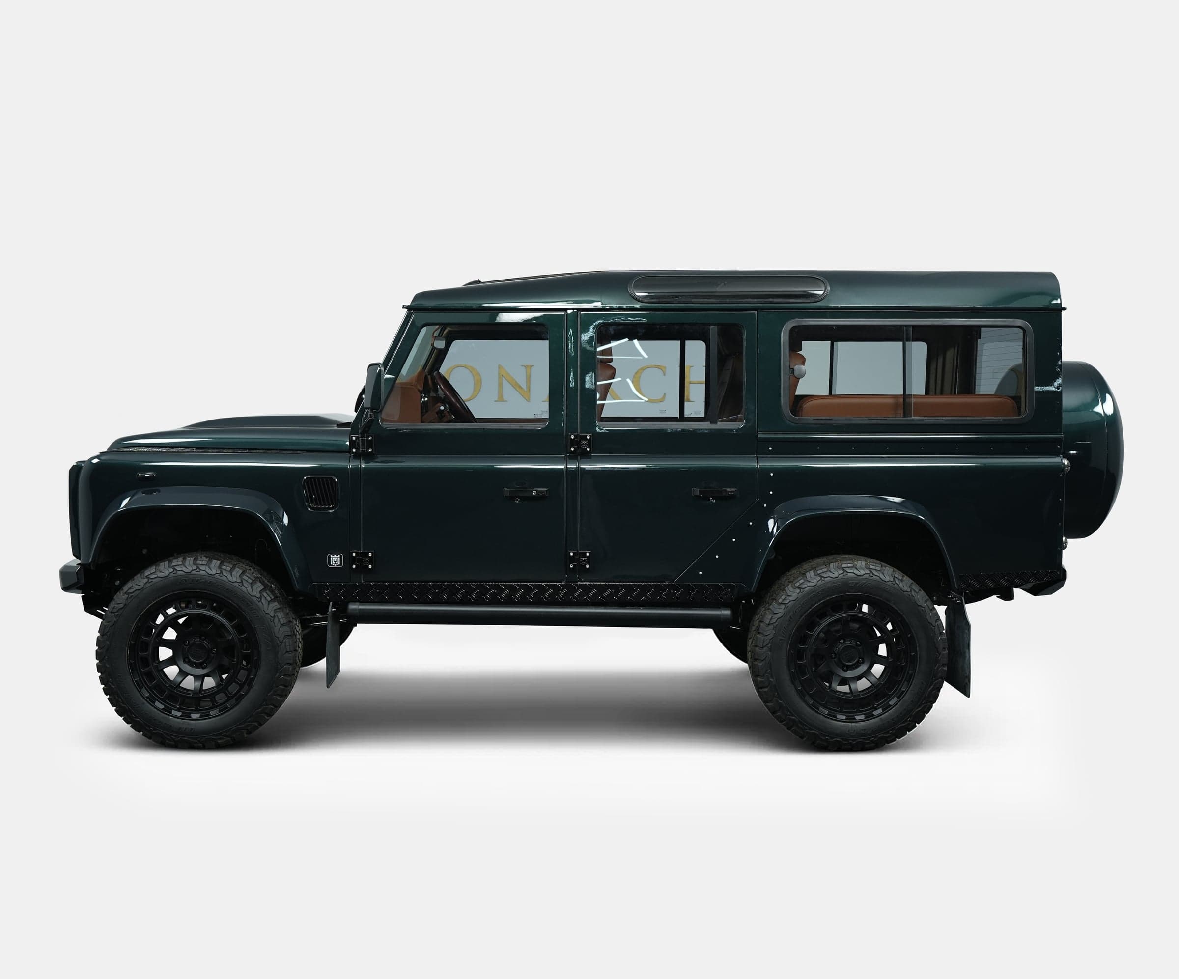 Side view of a bespoke Land Rover Defender in dark green with luxury tan interior