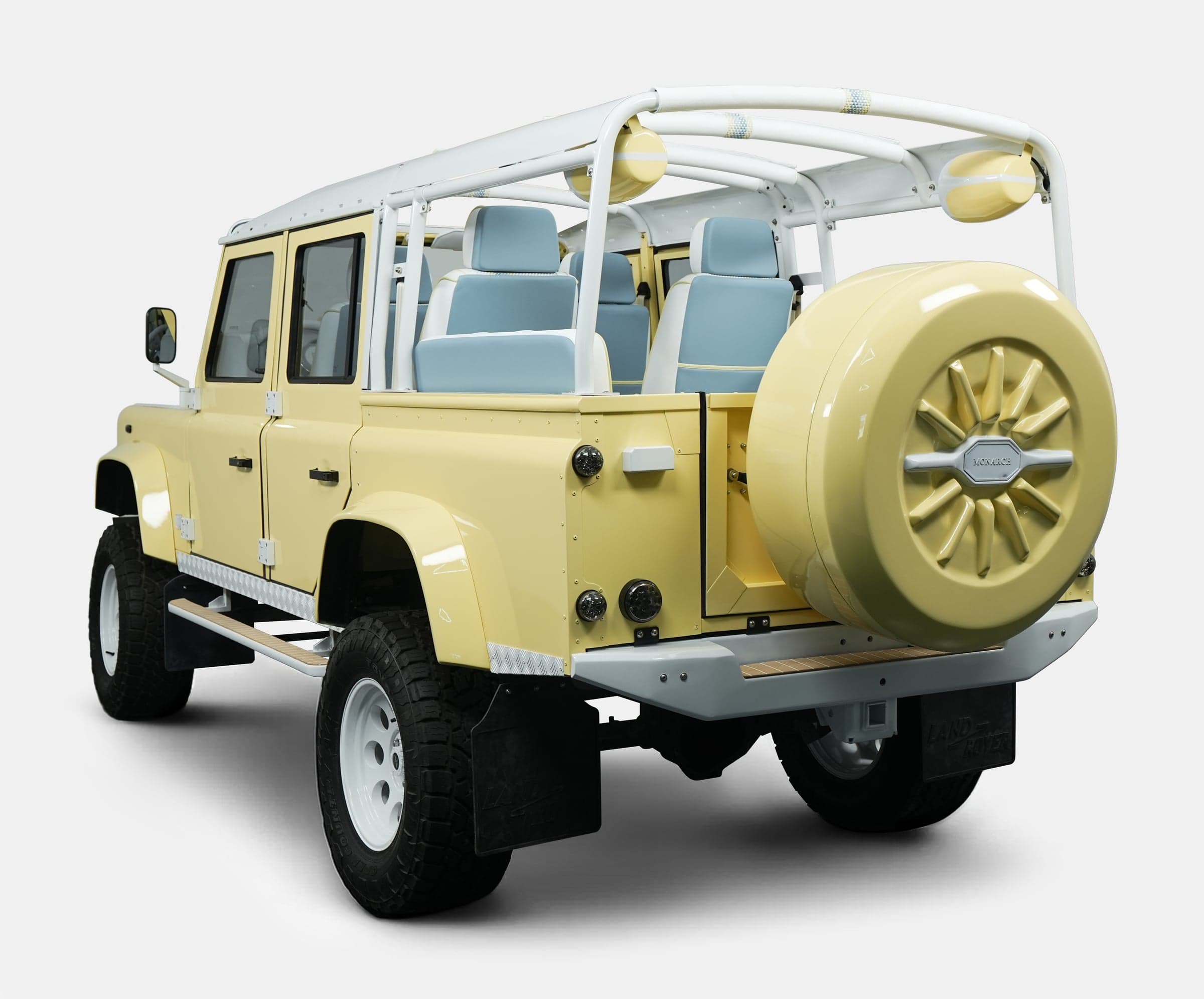 Rear view of a bespoke Land Rover Defender in pastel yellow with blue seats