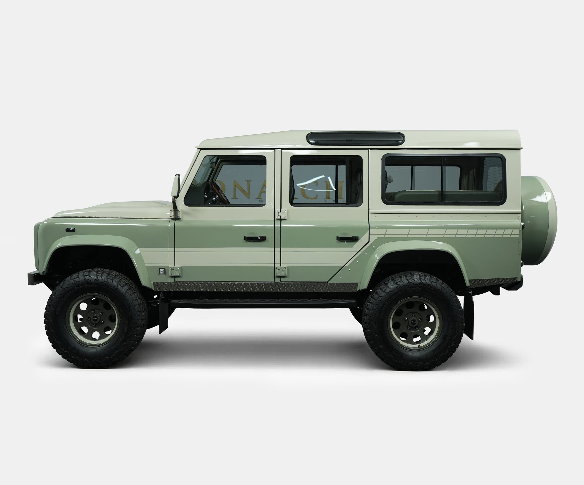 Side view of a custom Land Rover Defender in a soft green color with distinctive features