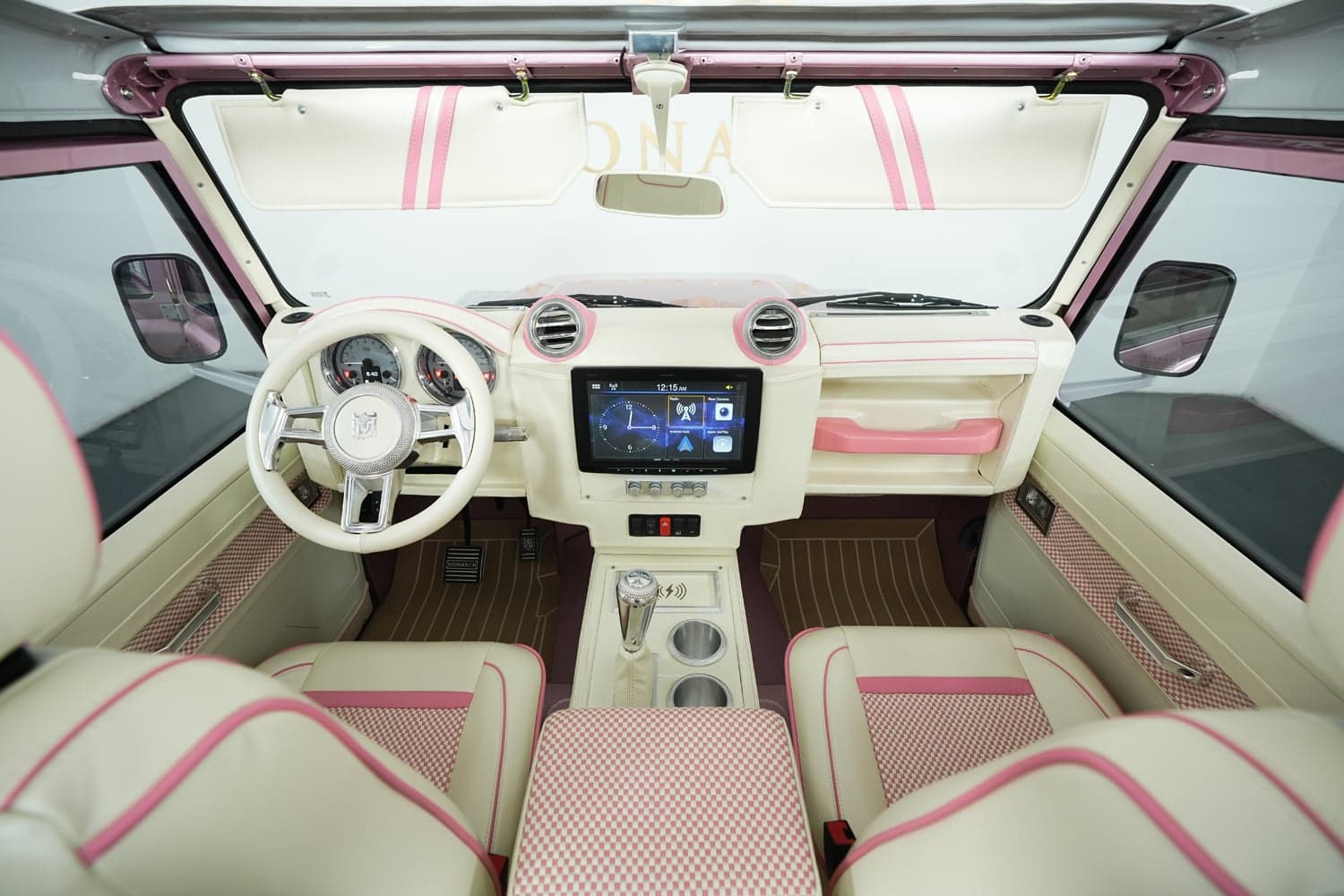 Bespoke Land Rover Defender interior featuring cream and pink leather, modern dashboard, and touchscreen display