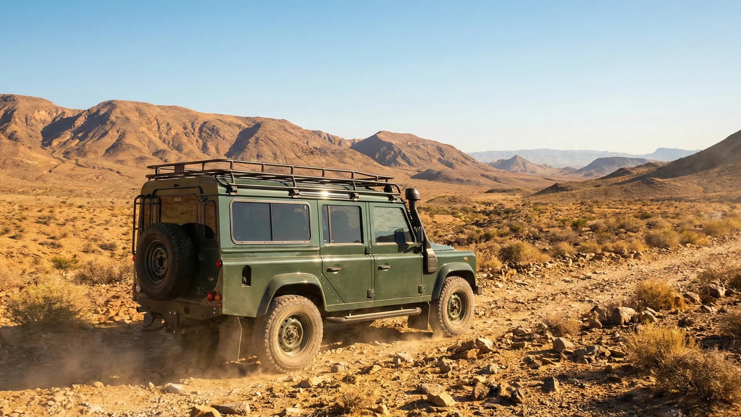 Bespoke Land Rover Defender driving through rocky desert terrain