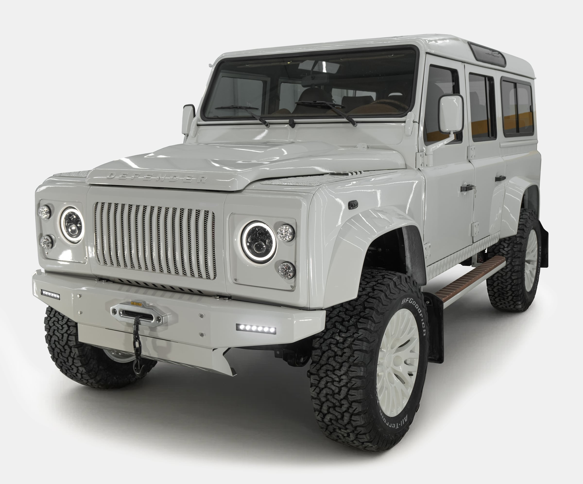 Front view of a custom Land Rover Defender in glossy white finish with modern headlights and rugged tires