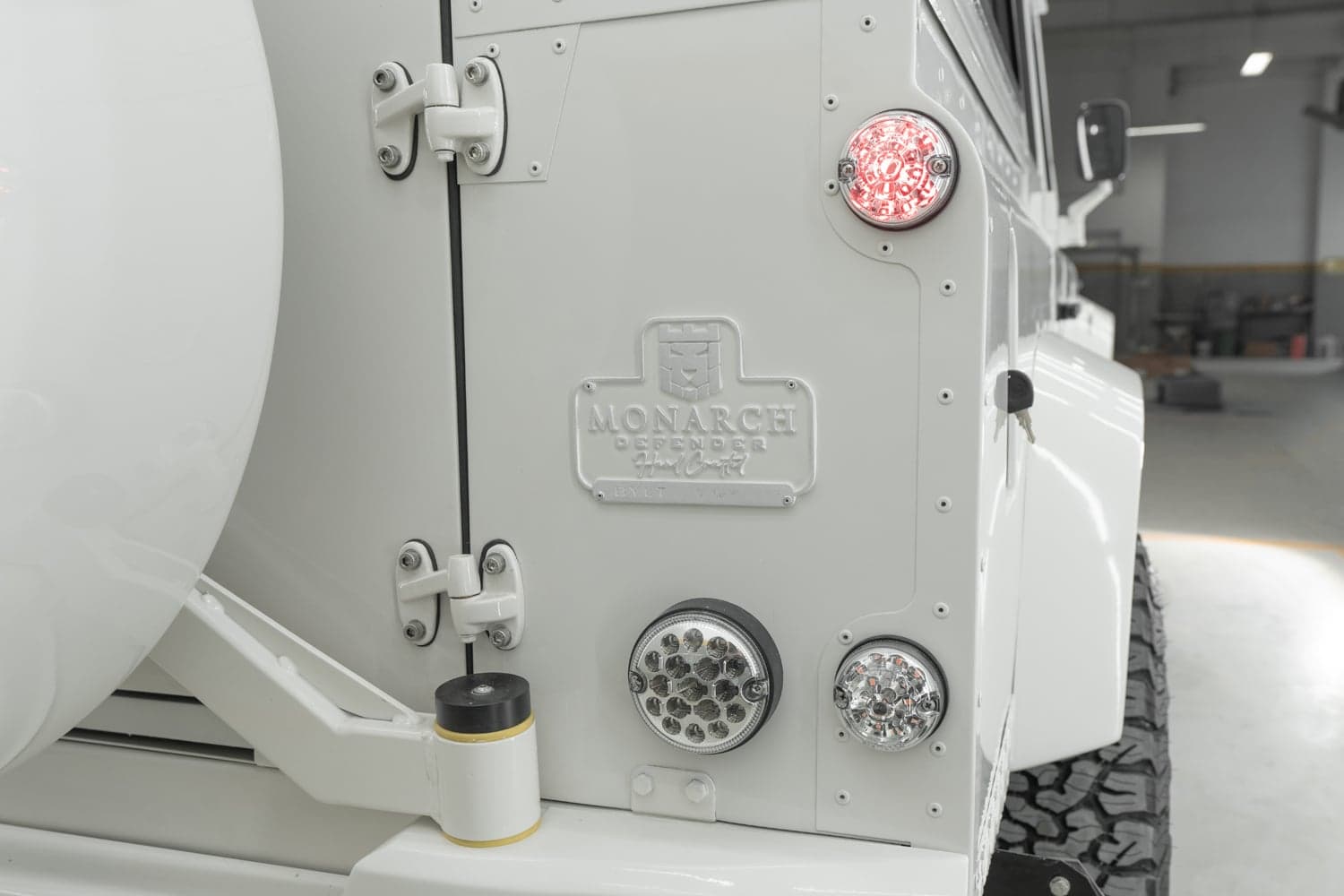 Detail Shot: Custom Rear Design Close-up of the rear of a custom Land Rover Defender featuring the Monarch Defender emblem and modern lighting