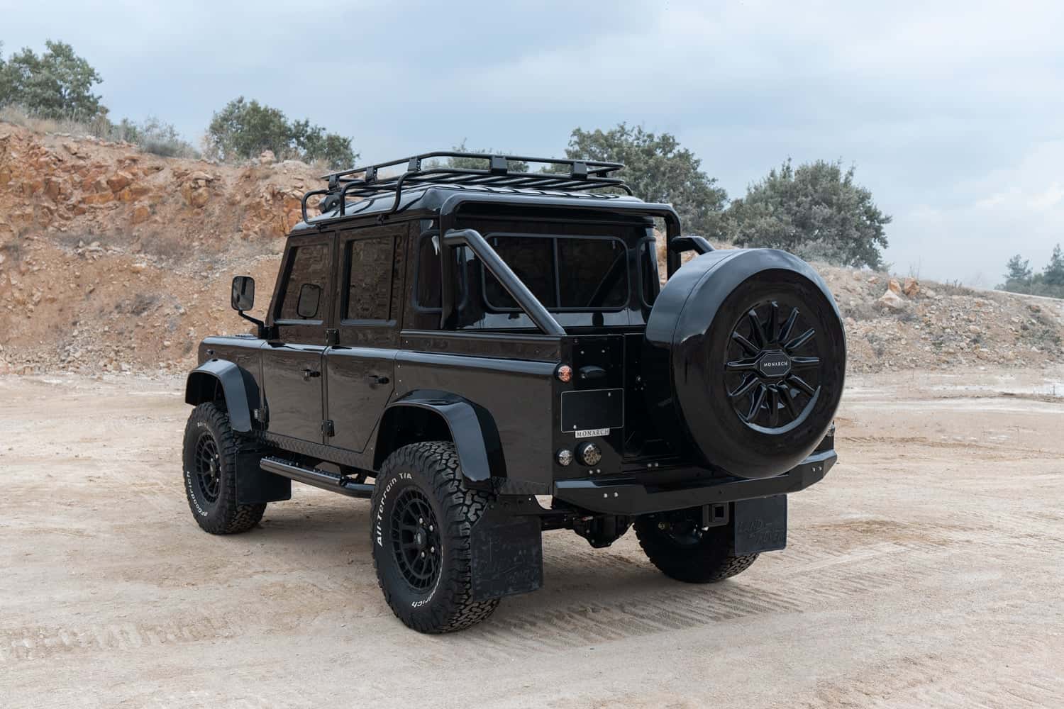 Rear View: Bespoke Land Rover Defender Custom Land Rover Defender in black with rugged tires and roof rack