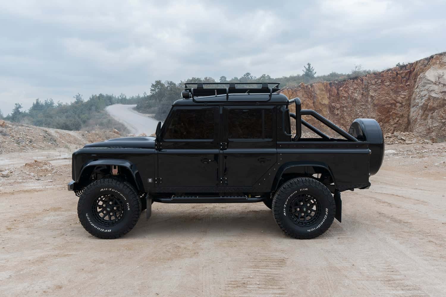 Side View: Bespoke Land Rover Defender Custom black Land Rover Defender on rugged terrain