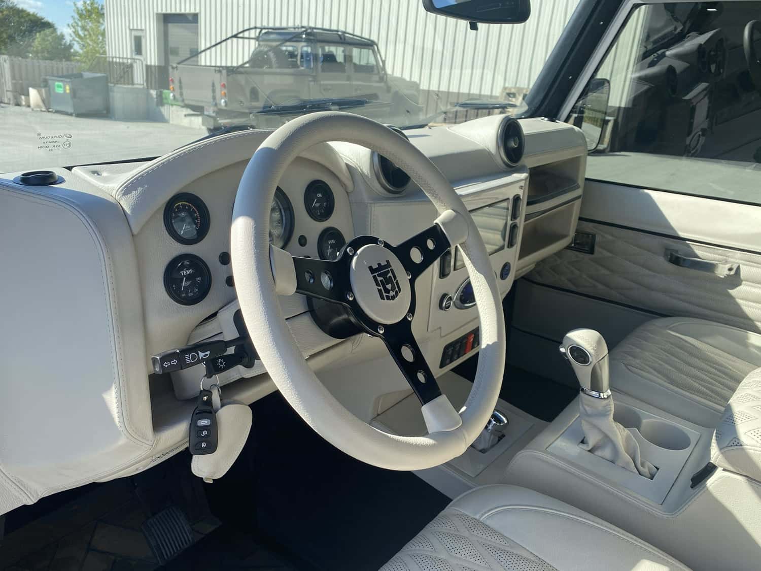 Interior Shot: Luxury Cabin Interior view of a custom Land Rover Defender featuring a premium white leather dashboard and steering wheel