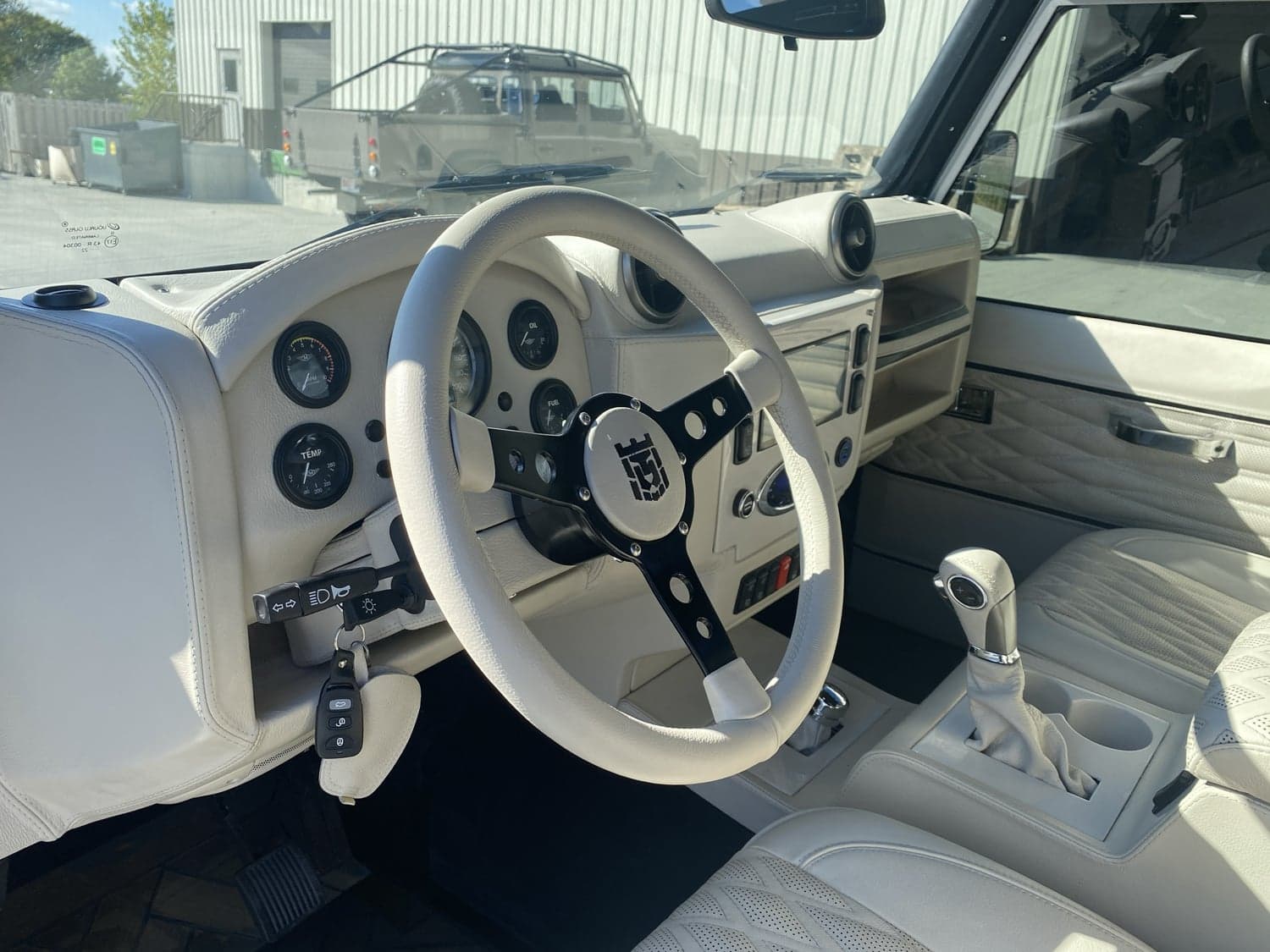 Interior Shot: Luxury Cabin Interior view of a custom Land Rover Defender featuring a premium white leather dashboard and steering wheel