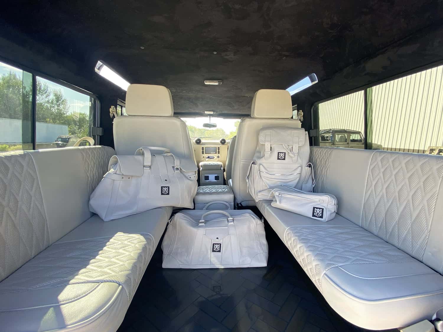 Interior Shot: Luxury Cabin Interior of a custom Land Rover Defender featuring premium white leather seating and designer bags