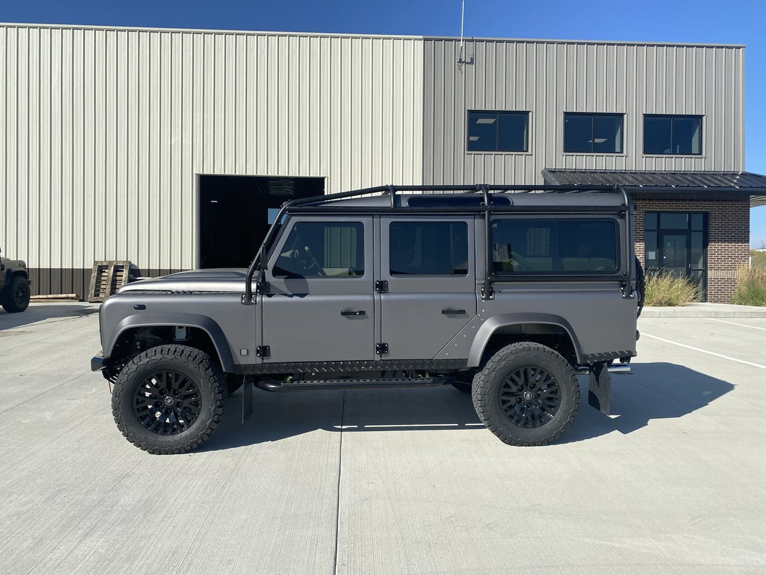 Side View: Custom Land Rover Defender Custom Land Rover Defender in matte gray parked outside a building