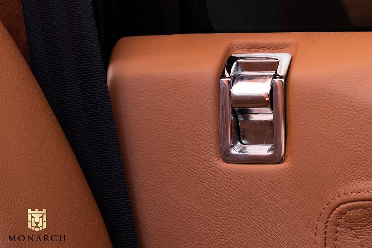 Detail Shot: Luxury Interior Features Close-up of a chrome seatbelt latch on a tan leather interior