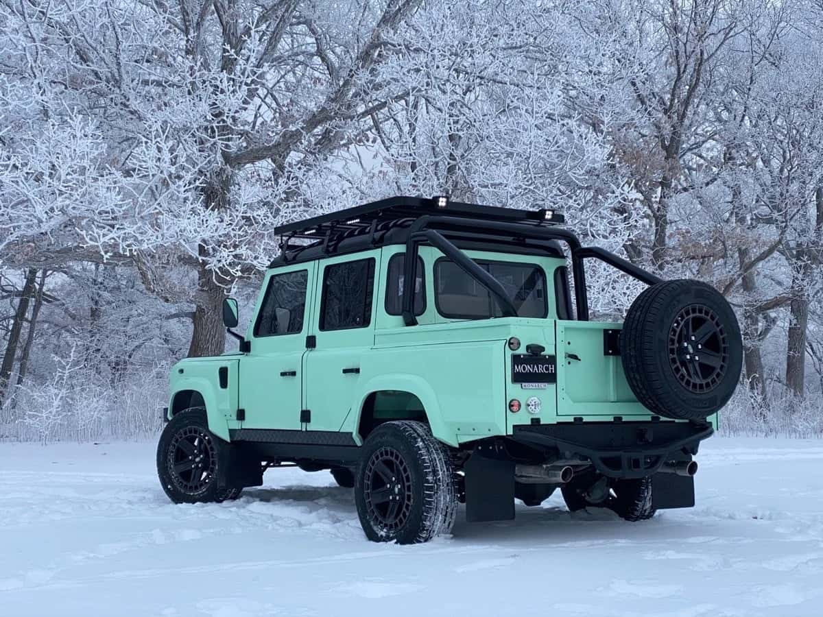 Rear View: Bespoke Land Rover Defender A mint green custom Land Rover Defender parked in a snowy landscape with frosty trees