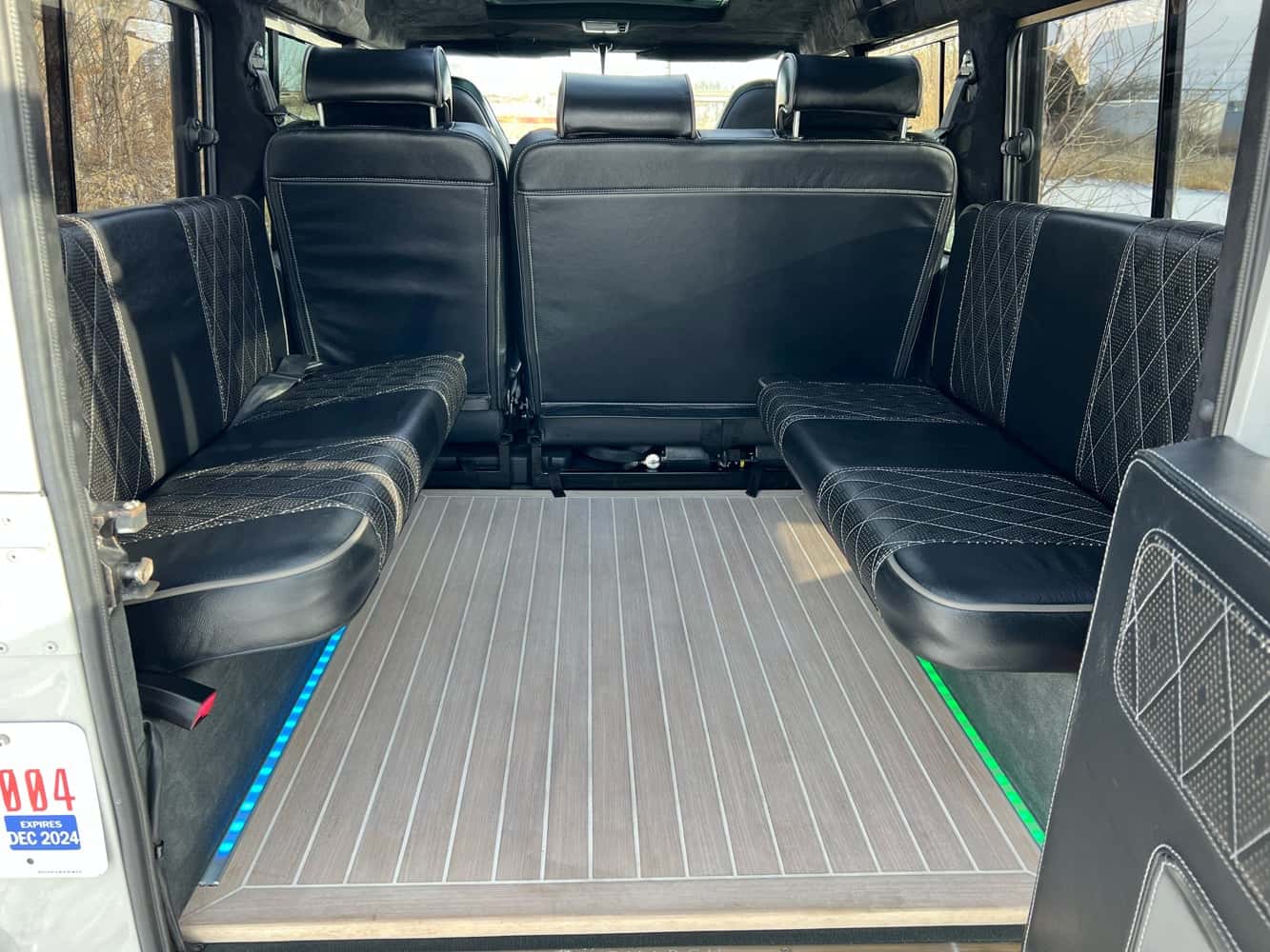 Interior Shot: Luxury Seating Interior view of a custom Land Rover Defender with luxurious black leather seating and wooden flooring