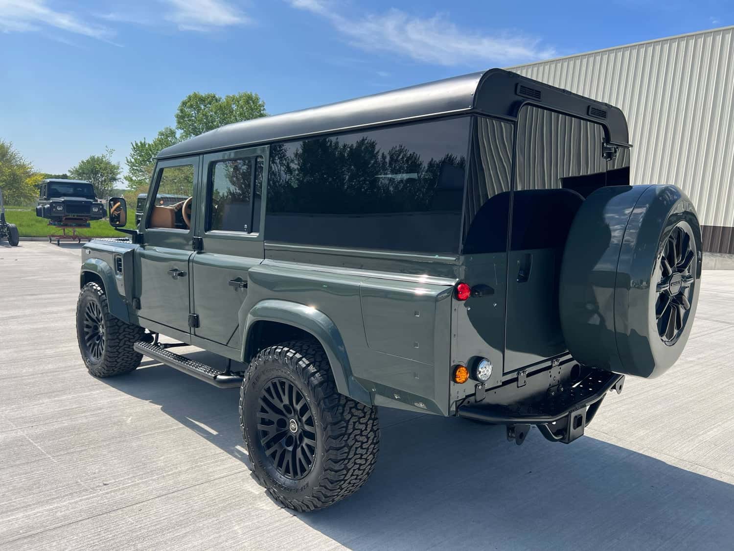 Rear View: Custom Land Rover Defender Rear view of a bespoke Land Rover Defender with a green finish and off-road tires