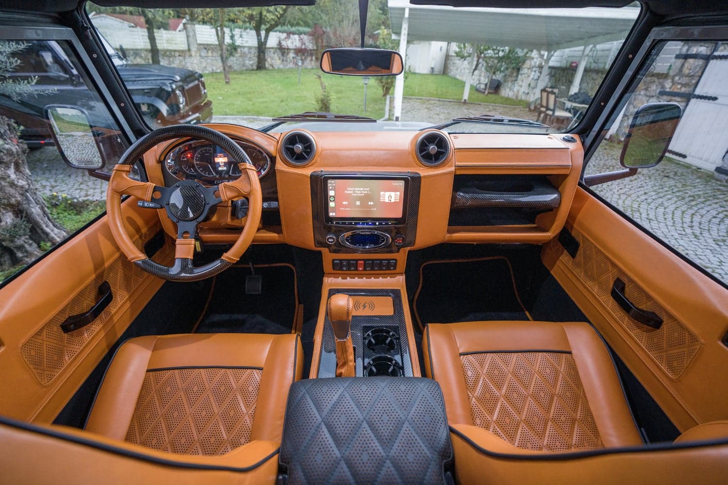 Interior Shot: Bespoke Cabin Luxury custom Land Rover Defender interior with orange leather upholstery and carbon fiber accents