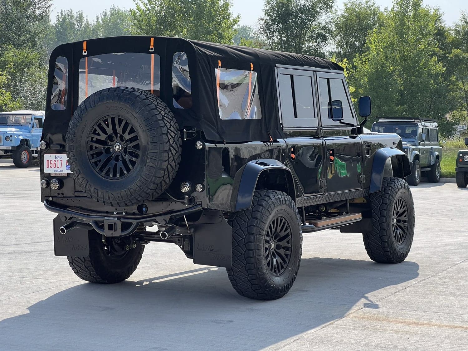 Rear View: Custom Land Rover Defender Black modified Land Rover Defender with a soft top and large tires