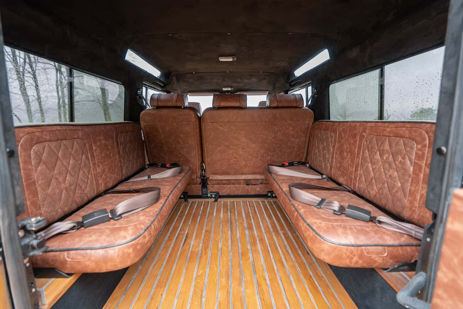 Interior Shot: Luxurious Back Seating Interior view of a custom Land Rover Defender featuring luxurious brown leather seating and wooden flooring