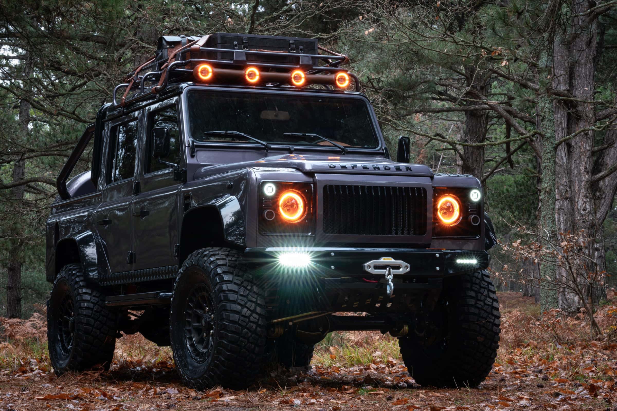 Front View: Custom Land Rover Defender Front view of a bespoke Land Rover Defender with custom modifications in a forest setting