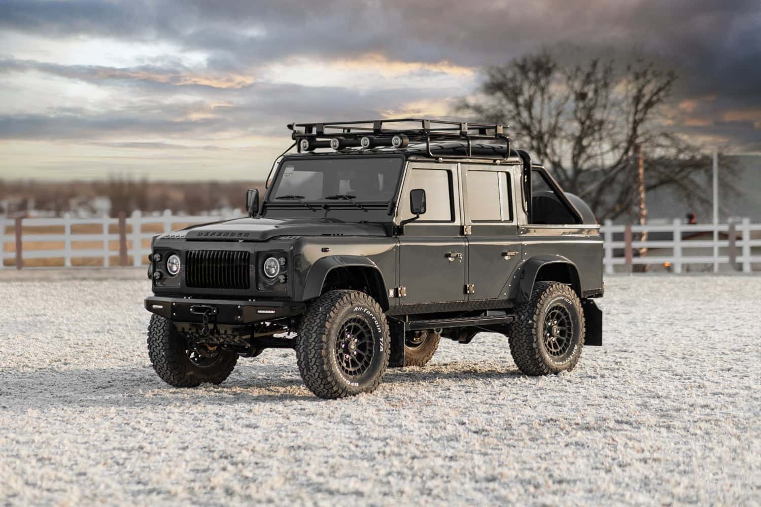 Front View: Custom Land Rover Defender Front view of a bespoke black Land Rover Defender with a roof rack and off-road tires