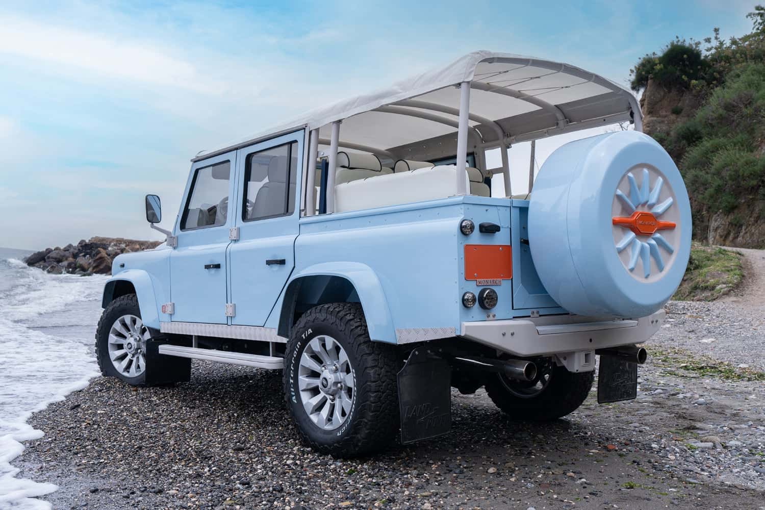 Studio Photo: Bespoke Land Rover Defender Custom light blue Land Rover Defender parked on a beach with white interior and spare tire cover