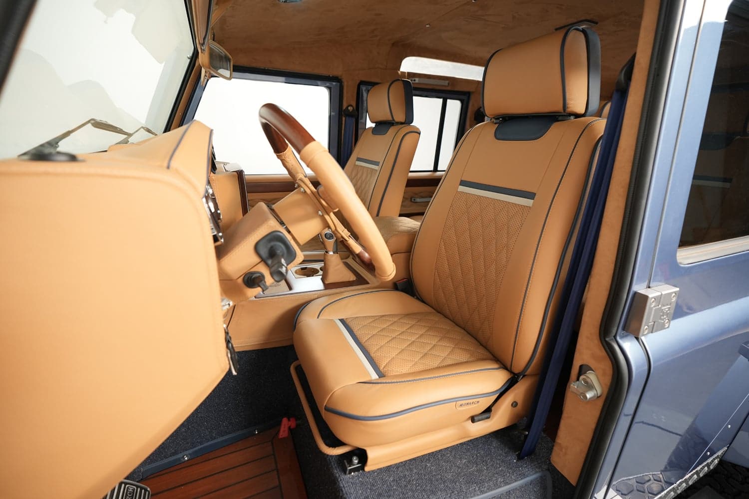 Interior Shot: Luxurious Cabin Design Custom Land Rover Defender interior featuring tan leather seats and wood accents